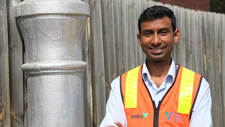 Project Manager, Kamal Gattu next to an upgraded sewer vent stack